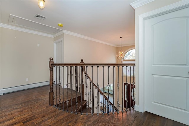 hall with a baseboard heating unit, wood finished floors, attic access, ornamental molding, and an upstairs landing