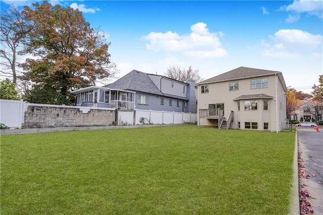 rear view of property with a sunroom, stairway, and a wooden deck