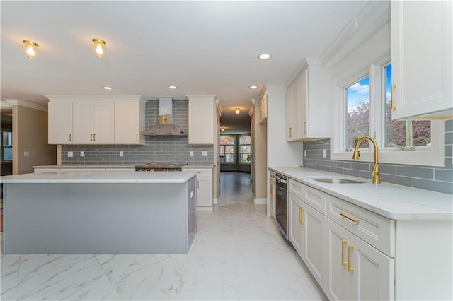 kitchen featuring wall chimney range hood, a sink, tasteful backsplash, white cabinets, and recessed lighting