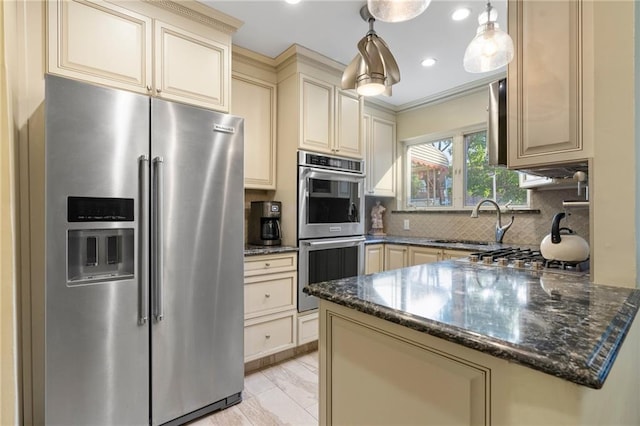 2472 Stuart St, Brooklyn, NY 11229 - kitchen with stainless steel appliances, cream cabinetry, backsplash, dark stone counters, and a peninsula