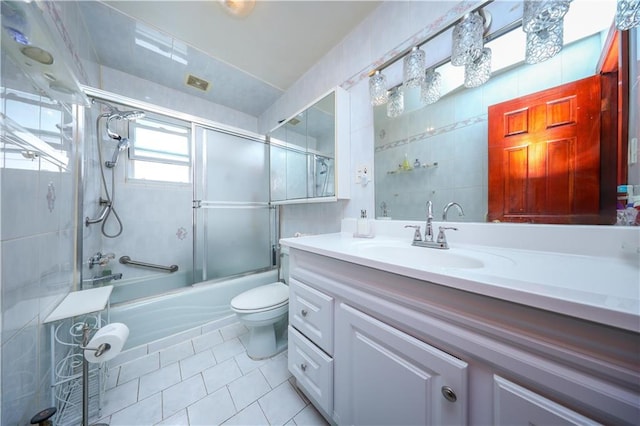 full bath featuring tile patterned floors, vanity, enclosed tub / shower combo, tile walls, and toilet