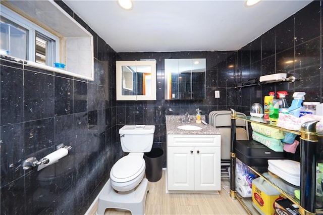 bathroom featuring tile walls, toilet, and vanity