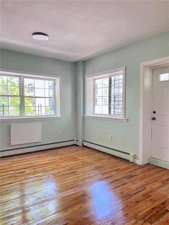 spare room featuring a baseboard radiator, healthy amount of natural light, and wood finished floors