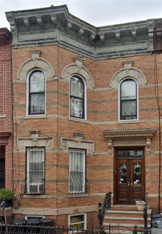 view of front facade featuring brick siding and french doors