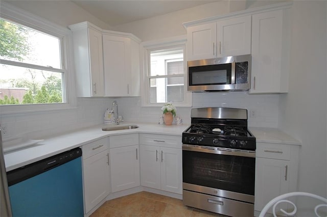 kitchen featuring appliances with stainless steel finishes, a sink, decorative backsplash, and white cabinets