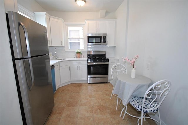 kitchen featuring appliances with stainless steel finishes, backsplash, light countertops, and white cabinets