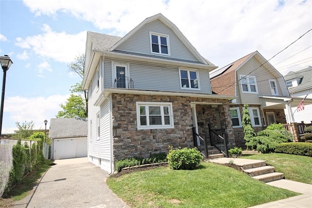 american foursquare style home with stone siding, a garage, and an outdoor structure
