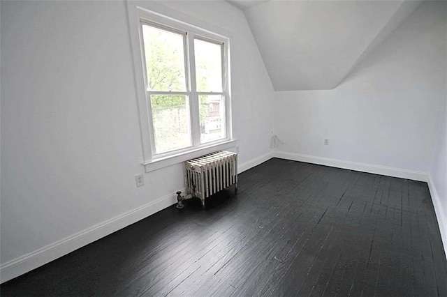 bonus room featuring radiator heating unit, lofted ceiling, dark wood-type flooring, and baseboards