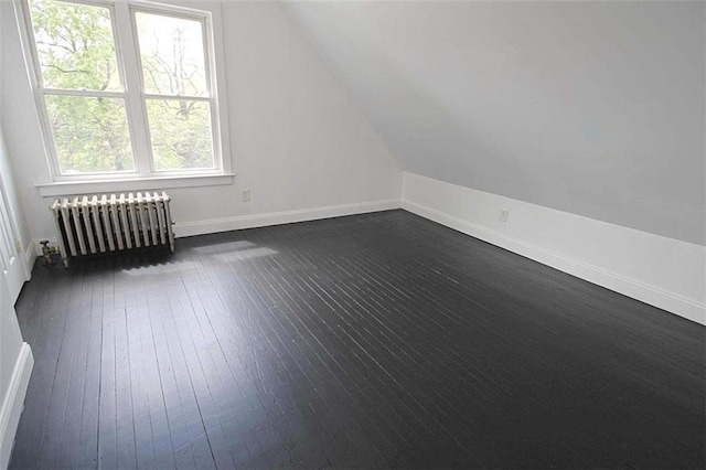 bonus room featuring radiator heating unit, vaulted ceiling, baseboards, and dark wood-style flooring
