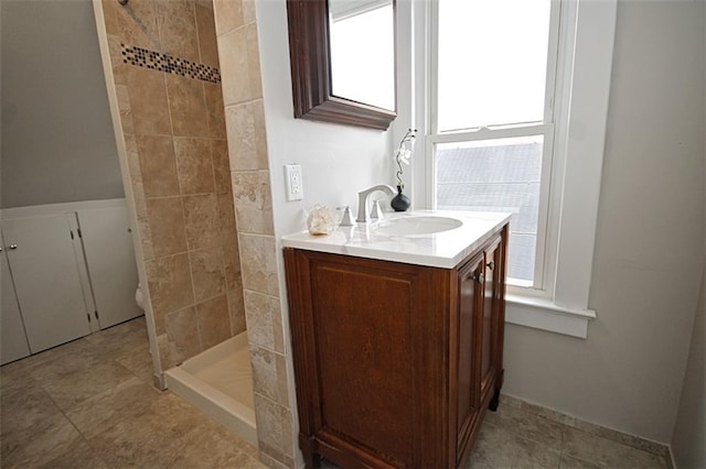 full bathroom with tiled shower and vanity
