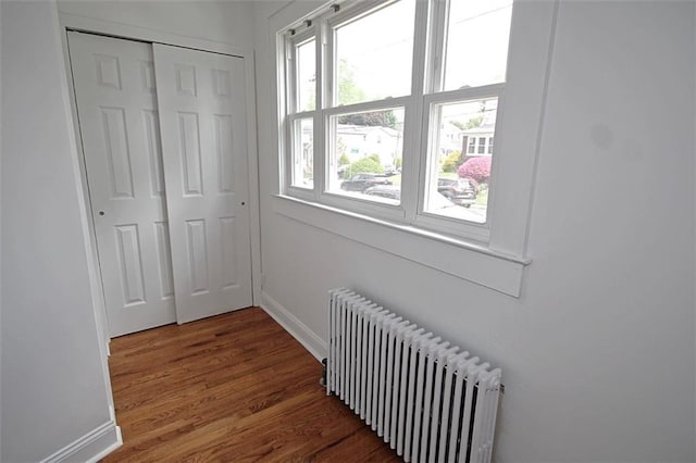 corridor featuring radiator, baseboards, and wood finished floors