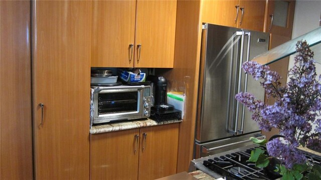 35 Seacoast Ter Unit 21F, Brooklyn, NY 11235 - kitchen with high quality fridge, brown cabinets, and light stone countertops