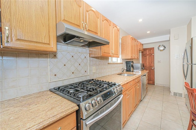 kitchen with stainless steel appliances, under cabinet range hood, a sink, light tile patterned floors, and tasteful backsplash