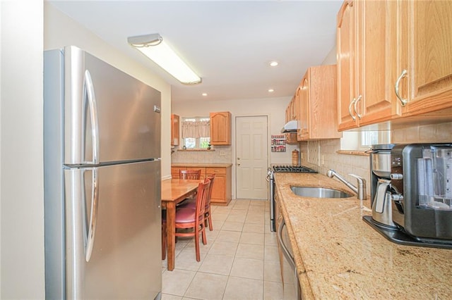 kitchen featuring appliances with stainless steel finishes, a sink, backsplash, light tile patterned flooring, and under cabinet range hood