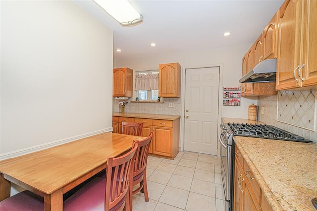 kitchen featuring under cabinet range hood, gas stove, light countertops, backsplash, and recessed lighting