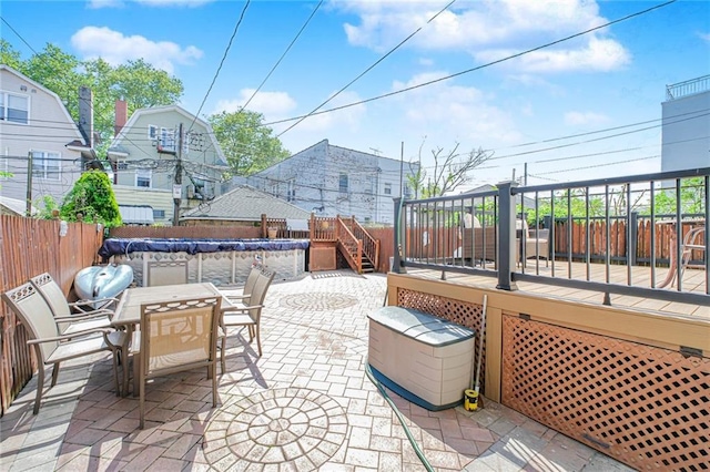 view of patio / terrace with a fenced backyard, a wooden deck, outdoor dining area, and stairs