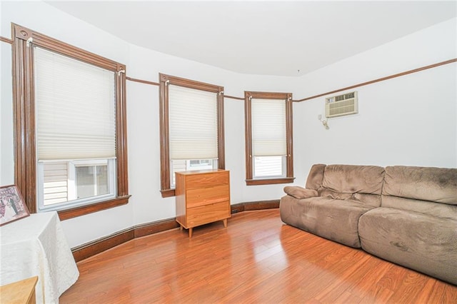 living area featuring an AC wall unit, wood finished floors, and baseboards