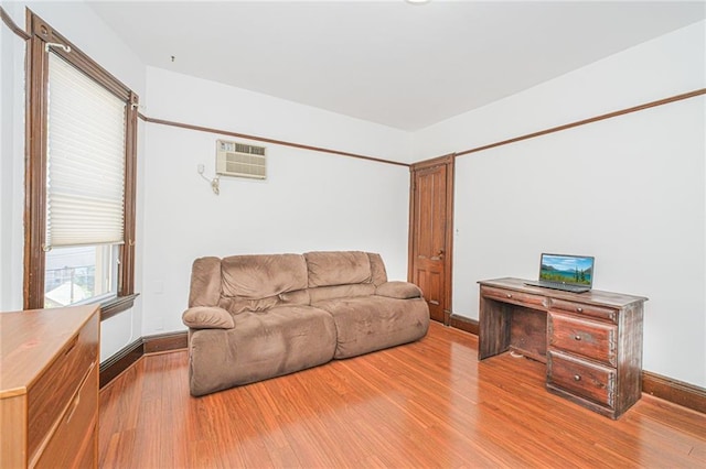 living area with a wall unit AC, wood finished floors, and baseboards
