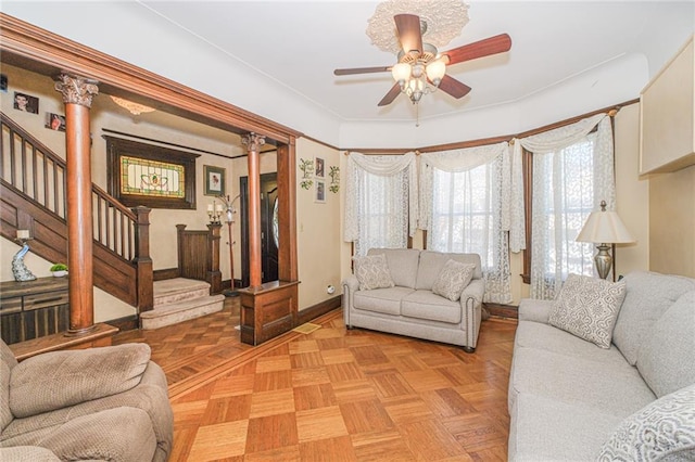 living area with a ceiling fan, baseboards, and stairs