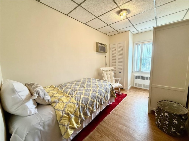 1413 81st St, Brooklyn, NY 11228 - bedroom featuring radiator heating unit, a drop ceiling, a wall unit AC, wood finished floors, and a closet