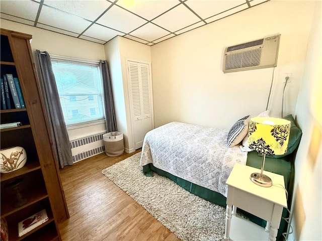 1413 81st St, Brooklyn, NY 11228 - bedroom featuring radiator heating unit, a wall mounted AC, a drop ceiling, wood finished floors, and a closet