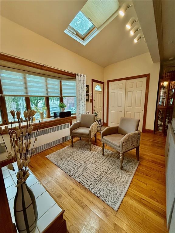 1413 81st St, Brooklyn, NY 11228 - living room featuring radiator heating unit, a skylight, and light wood-type flooring