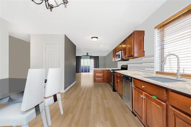 131 Stonegate Dr Unit 1, Staten Island, NY 10304 - kitchen featuring appliances with stainless steel finishes, a sink, light wood-type flooring, backsplash, and light stone countertops
