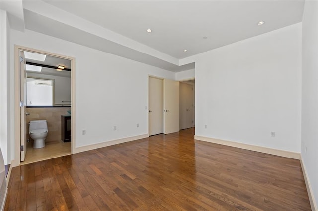 unfurnished bedroom with wood finished floors, ensuite bath, and recessed lighting