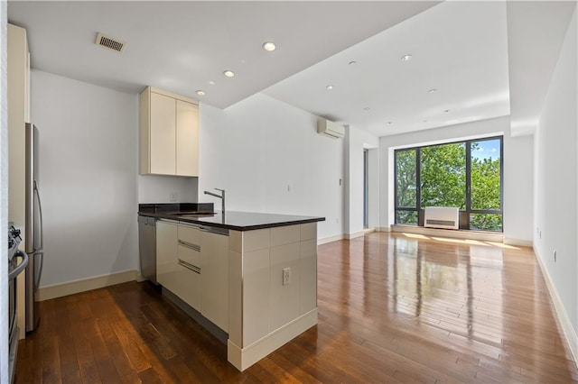 kitchen featuring a peninsula, open floor plan, an AC wall unit, dark wood-style floors, and dark countertops