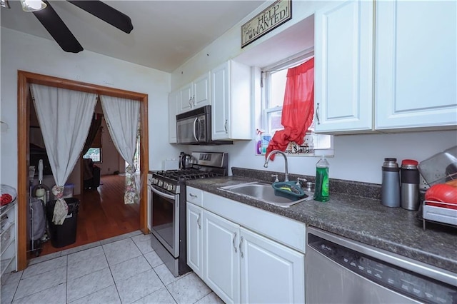 kitchen featuring stainless steel appliances, a sink, ceiling fan, white cabinetry, and dark countertops