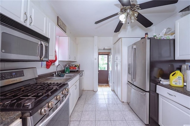 kitchen with appliances with stainless steel finishes, a sink, dark countertops, and white cabinets