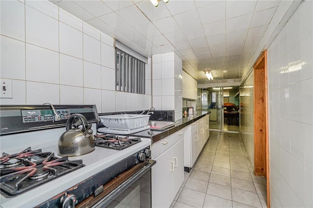 1519 71st St, Brooklyn, NY 11228 - kitchen with range, a sink, tile walls, white cabinets, and light tile patterned flooring