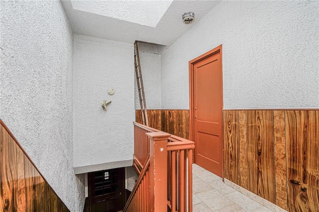1519 71st St, Brooklyn, NY 11228 - staircase with wood walls, a textured wall, a wainscoted wall, and a textured ceiling