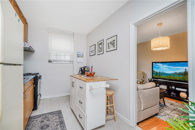 1519 71st St, Brooklyn, NY 11228 - kitchen featuring black gas range oven, freestanding refrigerator, extractor fan, a breakfast bar area, and white cabinetry