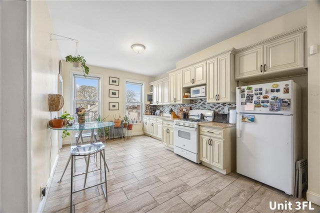 kitchen featuring white appliances, cream cabinetry, backsplash, and light countertops