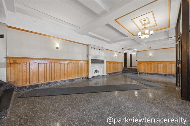 miscellaneous room featuring a wainscoted wall, coffered ceiling, beam ceiling, and a chandelier