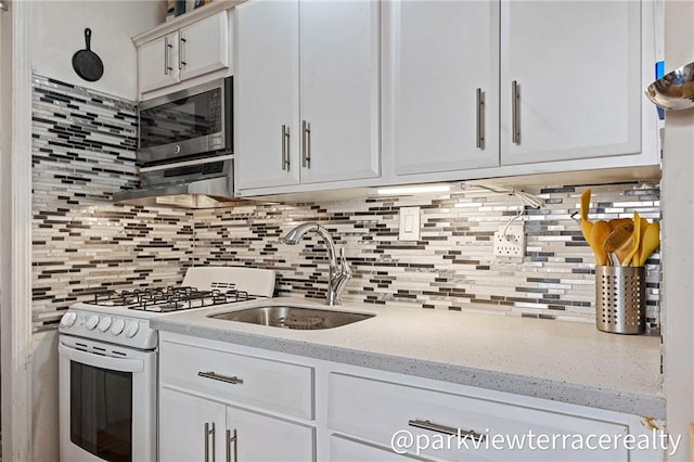 kitchen featuring a sink, white gas range, stainless steel microwave, and white cabinets