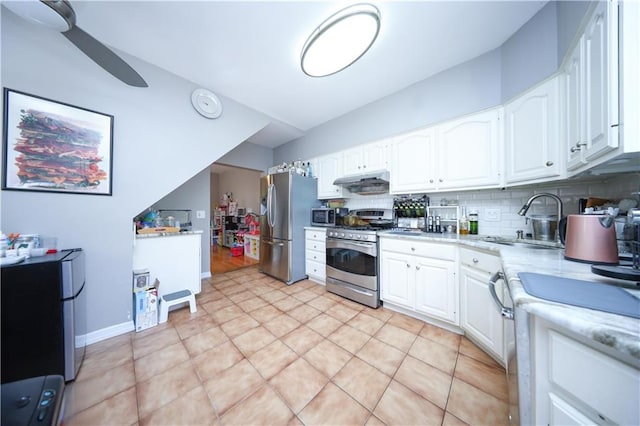 kitchen with appliances with stainless steel finishes, a sink, white cabinets, tasteful backsplash, and lofted ceiling