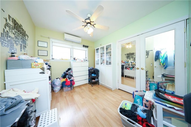 interior space with a wall mounted AC, french doors, wood finished floors, and a ceiling fan
