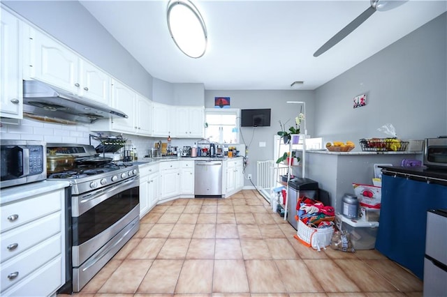 kitchen featuring stainless steel appliances, under cabinet range hood, white cabinets, a ceiling fan, and tasteful backsplash