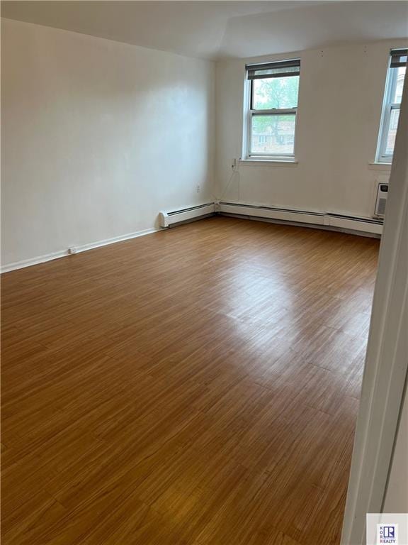 unfurnished room featuring plenty of natural light, dark wood-style floors, baseboards, and a baseboard radiator