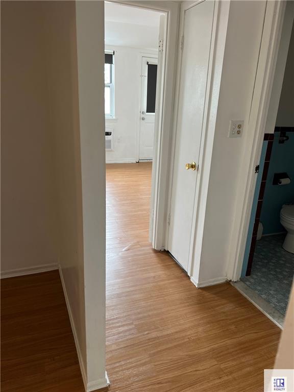 corridor with light wood-style floors and baseboards
