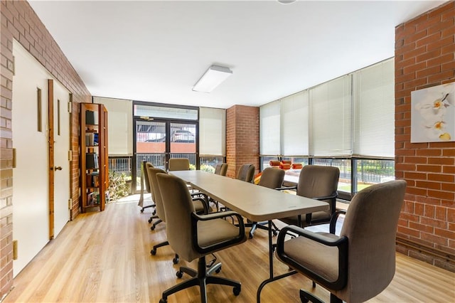 dining space featuring a wall of windows, light wood-type flooring, and brick wall