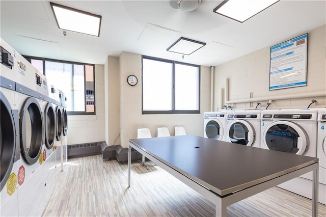 shared laundry with concrete block wall, washing machine and dryer, and healthy amount of natural light
