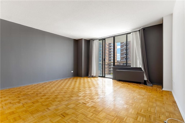unfurnished room featuring baseboards, a wall of windows, and a textured ceiling