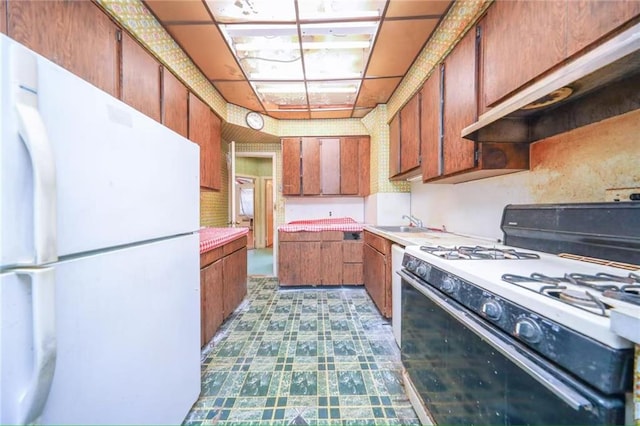 2327 E 16th St, Brooklyn, NY 11229 - kitchen with white appliances, light countertops, brown cabinets, dark flooring, and a sink