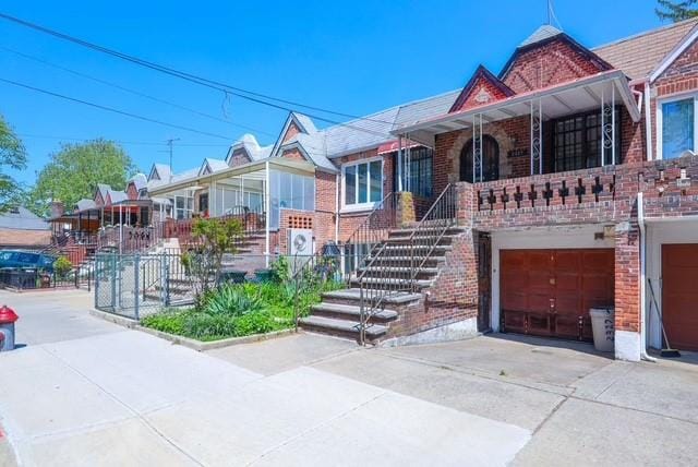 2327 E 16th St, Brooklyn, NY 11229 - view of front of property featuring brick siding, driveway, an attached garage, and covered porch