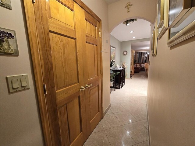 corridor featuring arched walkways, light tile patterned flooring, and recessed lighting