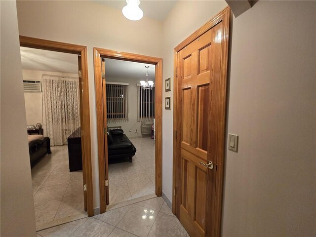 hallway with a chandelier, light tile patterned floors, and baseboards
