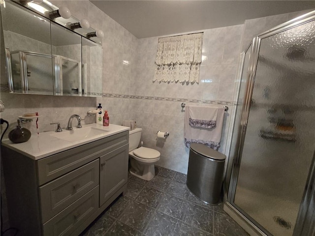 bathroom featuring tile walls, a shower stall, vanity, toilet, and tile patterned flooring